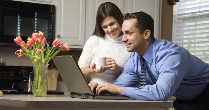 man and woman looking at laptop in kitchen